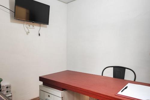 a kitchen with a wooden counter top with a black chair at RedDoorz Syariah near Telanaipura Jambi in Jambi