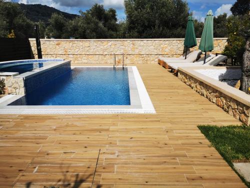 a swimming pool in a yard with a wooden floor at Villa MATA - 600m² with Private Pool and Jacuzzi in Kalithies