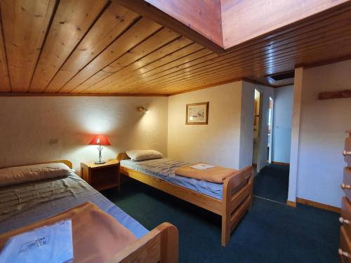 une chambre avec deux lits et un plafond en bois dans l'établissement Meijotel - 508 - Appart duplex - 6 pers, à Les Deux Alpes