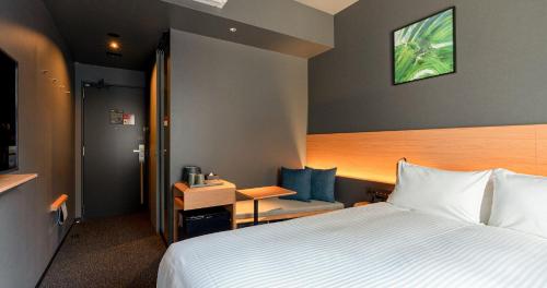 熊本市にあるグリッズプレミアムホテル熊本の大きなベッドとデスクが備わるホテルルームです。
