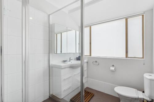Baño blanco con lavabo y espejo en Silver Sands Holiday & Beach House, en Mandurah