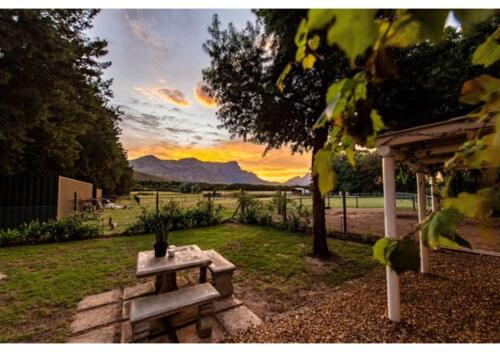 - une table de pique-nique dans une cour avec un coucher de soleil dans l'établissement Franschhoek Cottages, à Franschhoek