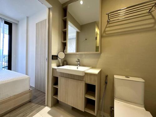 een badkamer met een wastafel, een toilet en een spiegel bij 2 Bedroom Skypark Condo Laguna in Bang Tao Beach