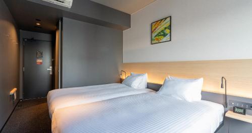 a bedroom with a large bed with white sheets at Grids Premium Hotel Kumamoto in Kumamoto