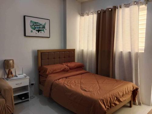 a bedroom with a bed and a window with curtains at Cozy studio unit in a condominium in Iloilo City