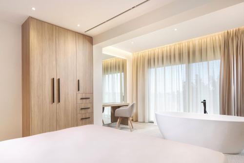 a bedroom with a large white tub and a desk at Mamfredas Luxury Residence in Plános