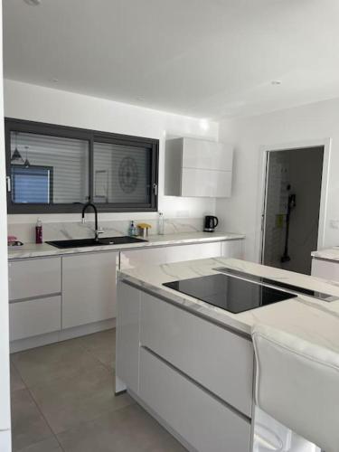 une cuisine blanche avec des armoires blanches et un évier dans l'établissement Maison au cœur des Pyrénées !, à Ayzac-Ost