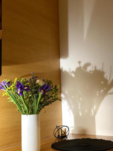 a white vase with purple flowers on a table at Golem in Prague