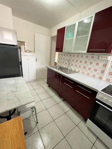 a kitchen with red cabinets and a white tile floor at Réf 531, Seignosse Océan, Appartement proche de la plage et du centre, 4 personnes in Seignosse