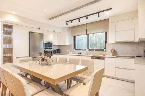 a kitchen with white cabinets and a wooden table and chairs at Mamfredas Luxury Residence in Plános