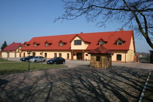 a large building with a red roof and cars parked at Folwark Polski in Ostrów Wielkopolski