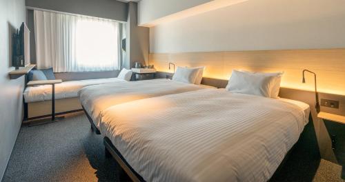 a hotel room with two beds and a window at Grids Premium Hotel Kumamoto in Kumamoto