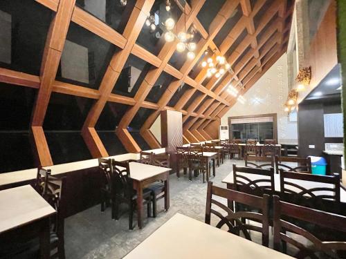 un restaurante con techos de madera, mesas y sillas en Hotel KP ! Puri near-sea-beach-and-temple fully-air-conditioned-hotel with-lift-and-parking-facility en Puri