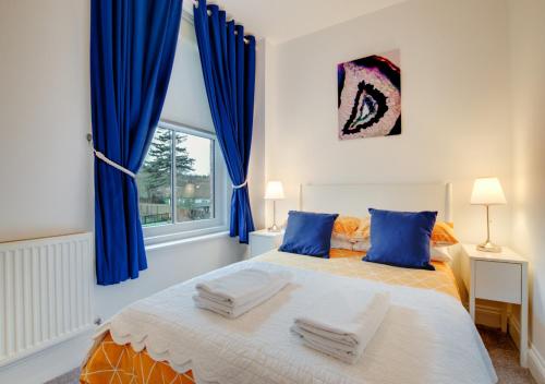 a bedroom with a large bed with blue curtains at Happy Valley in Cromer