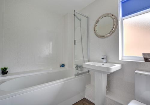 a white bathroom with a sink and a mirror at Happy Valley in Cromer