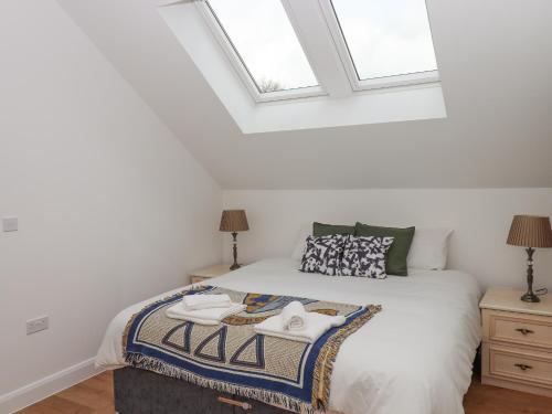a bedroom with a bed with white sheets and windows at Narracott Down in South Molton