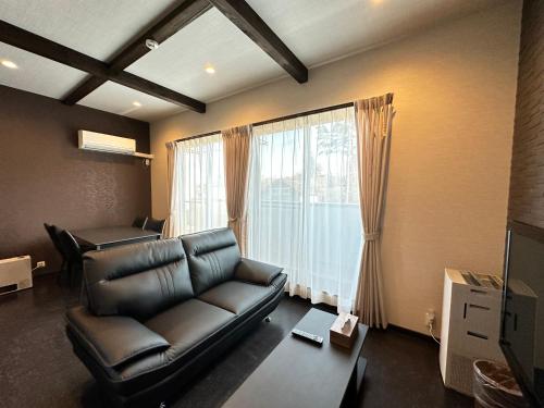 a living room with a leather couch and a window at 72 Mt View - B棟 - in Fujikawaguchiko