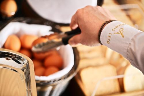 a person holding a wine bottle next to a basket of eggs at Hotel Artemis in Oradea