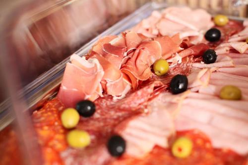a tray of food with meat and grapes on it at Hotel Artemis in Oradea