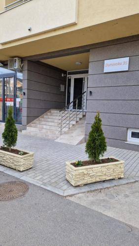 two potted trees in baskets in front of a building at Stan na dan Apartman S in Požarevac