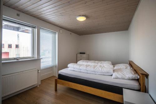 a bedroom with a bed with white sheets and a window at 4-bedroom house with sea view and hot tub in Ilulissat