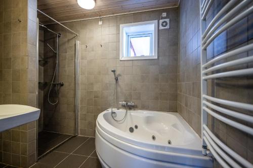 a bathroom with a tub and a toilet and a window at 4-bedroom house with sea view and hot tub in Ilulissat