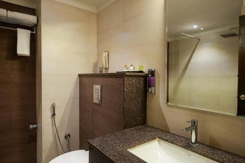 a bathroom with a sink and a mirror at Grand Continent Malleshwaram A Sarovar Portico Affiliate Hotel in Bengaluru
