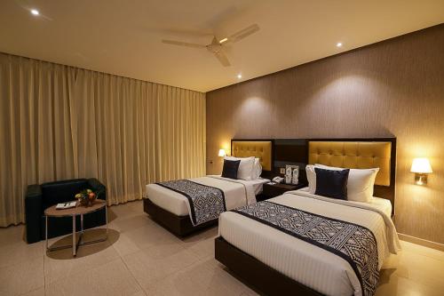 a hotel room with two beds and a chair at Grand Continent Malleshwaram A Sarovar Portico Affiliate Hotel in Bangalore