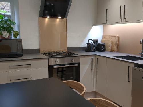 a kitchen with white cabinets and a stove top oven at Trade Digs Ryeleaze Road in Stroud