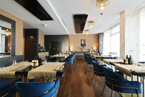 a dining room with tables and blue chairs at Hotel Artemis in Oradea