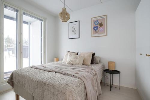 a white bedroom with a bed and a window at LadyCrane apartment, sauna and parking in Kirkkonummi