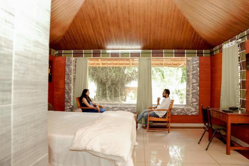 zwei Personen in einem Zimmer mit einem Bett und einem Fenster in der Unterkunft Misty Night Jungle Side Resort in Pulpally
