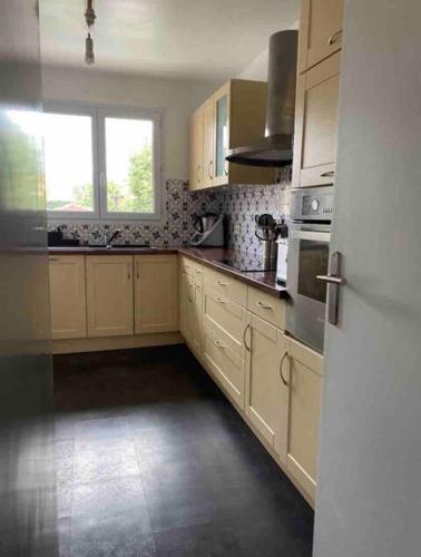 une grande cuisine avec des armoires blanches et une fenêtre dans l'établissement Le Parisien - Bel Appartement à 10mn de Paris, à Suresnes