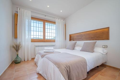 two beds in a bedroom with white walls and windows at Majordoms - Cal Sabater in Las Escaulas