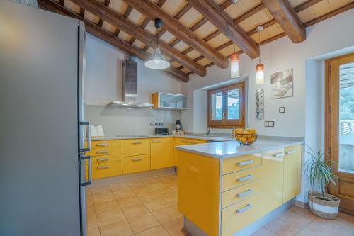 a kitchen with yellow cabinets and a wooden ceiling at Majordoms - Cal Sabater in Las Escaulas