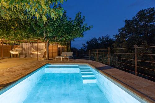 a swimming pool next to a deck with a tree at Majordoms - Cal Sabater in Las Escaulas
