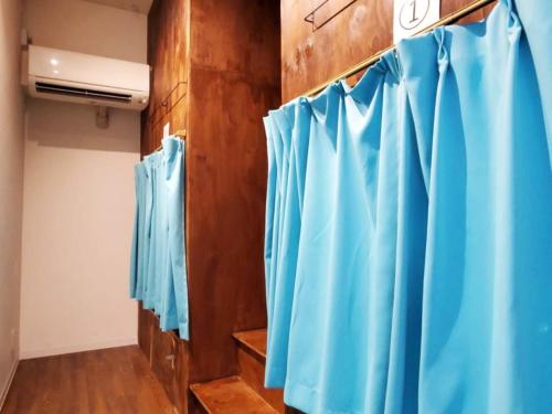 une rangée de rideaux de douche bleus dans une chambre dans l'établissement ゲストハウス EZO Run Sapporo 札幌中心部でシンプルな滞在ができるホステル, à Sapporo