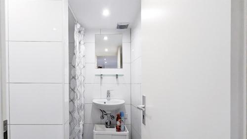 ein weißes Badezimmer mit einem Waschbecken und einem Spiegel in der Unterkunft ALFA Ludwigsburg City 3 Zimmer 5 Betten Küche Netflix INET WM in Ludwigsburg