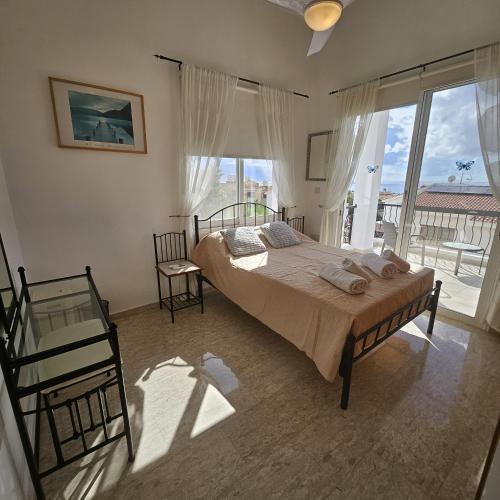 ein Schlafzimmer mit einem Bett und einem großen Fenster in der Unterkunft Villa Athena in Peyia