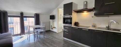 uma cozinha com armários pretos e uma mesa com cadeiras em Design Loft Monteponi em Turim