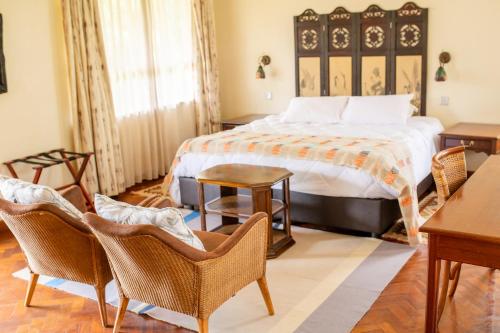 a bedroom with a bed and two chairs and a table at Zereniti House in Muyaka