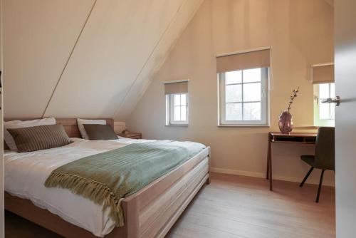 a bedroom with a bed and a desk and windows at Hello Zeeland - vakantiewoning Knuitershoek 70 