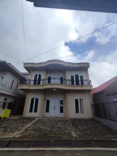 Cette maison blanche dispose d'un balcon. dans l'établissement Homestay wahyu abadi 2 syariah, à Diyeng