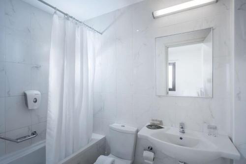 La salle de bains blanche est pourvue de toilettes et d'un lavabo. dans l'établissement Hersonissos Village Hotel & Bungalows, à Chersónissos
