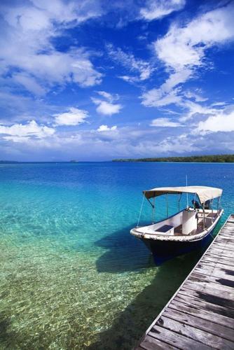 a boat sitting on the water next to a dock at Ratua Private Island Resort in Aimbuei Bay