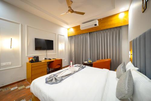 a hotel room with a white bed and a television at Gold Nest Rubystone Heritage in Udaipur