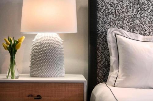 a lamp on a nightstand next to a bed with a vase of flowers at Hanza Tower Gold - 24 Pool & SPA in Szczecin