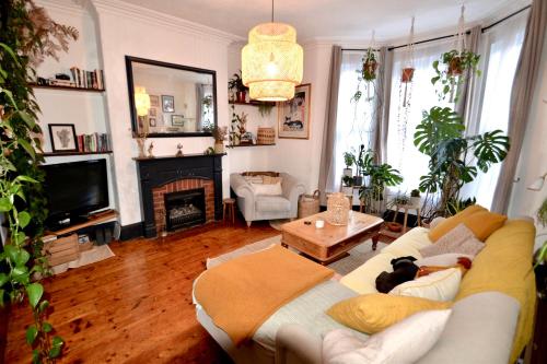 een woonkamer met een witte bank en een open haard bij Bright and cosy, central 3 bedroom home in Plymouth