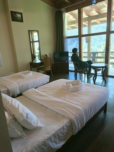 two beds in a room with a person sitting in a chair at Whispering Woods Resort in Thimphu