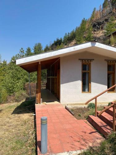 uma pequena casa com um alpendre e uma escadaria em Whispering Woods Resort em Thimphu